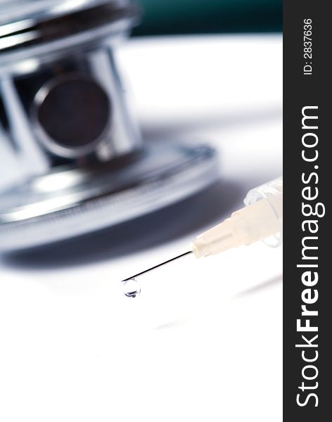 Stethoscope and a syringe in green on an isolated white background