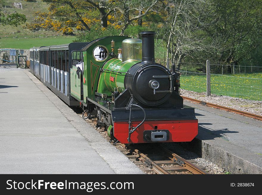 Narrow gauge steam train arriving at a station platform