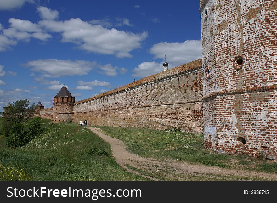Long red fort wall with path along it. Summer, sunny day. Old Russian Town. Long red fort wall with path along it. Summer, sunny day. Old Russian Town