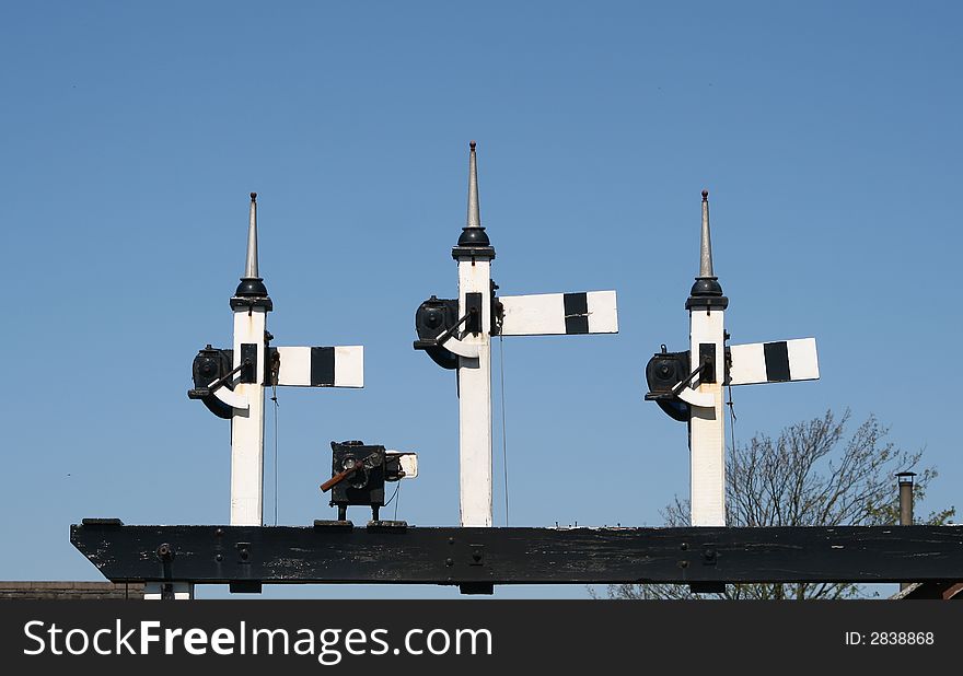 Railway signals set across the railway tracks against a blue sky