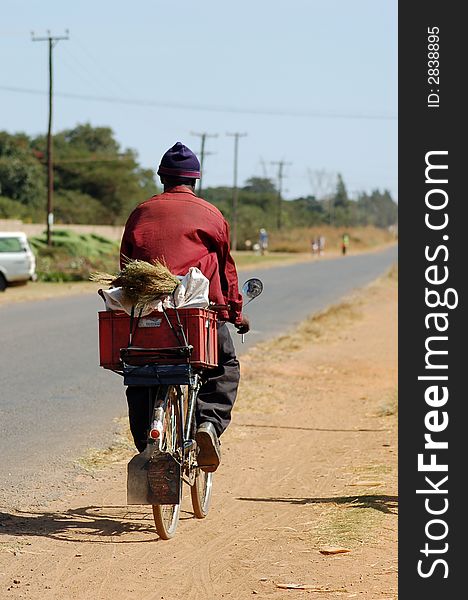 An african man transporting goods on a bicycle