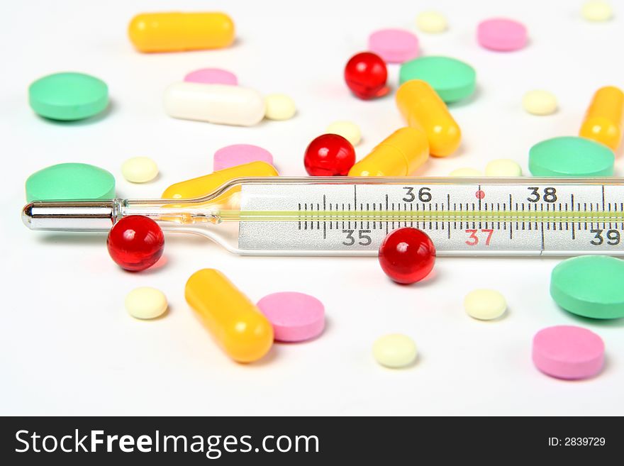 thermometer and pills on white background