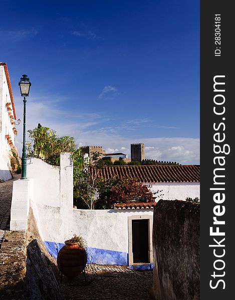 Old beautiful houses in medieval city of Obidos, Portugal with castle walls in background