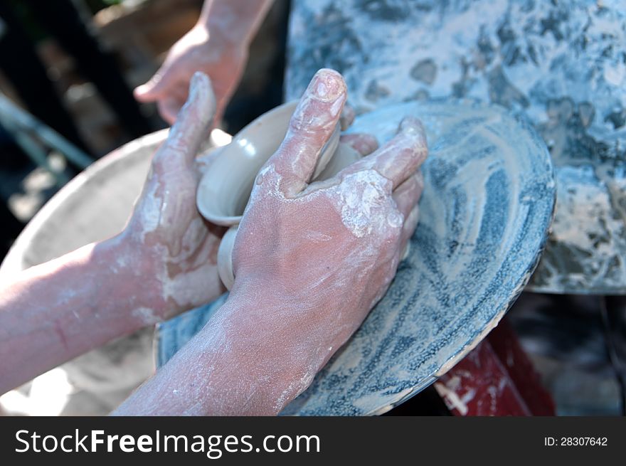 The hand of the Potter remove the product from the clay on the Potter's wheel. The hand of the Potter remove the product from the clay on the Potter's wheel