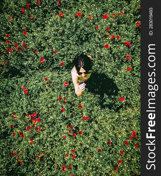 Top aerial girl smell flower in poppy field spring nature. Red green poppy flower field .Concept of woman wellness and freedom