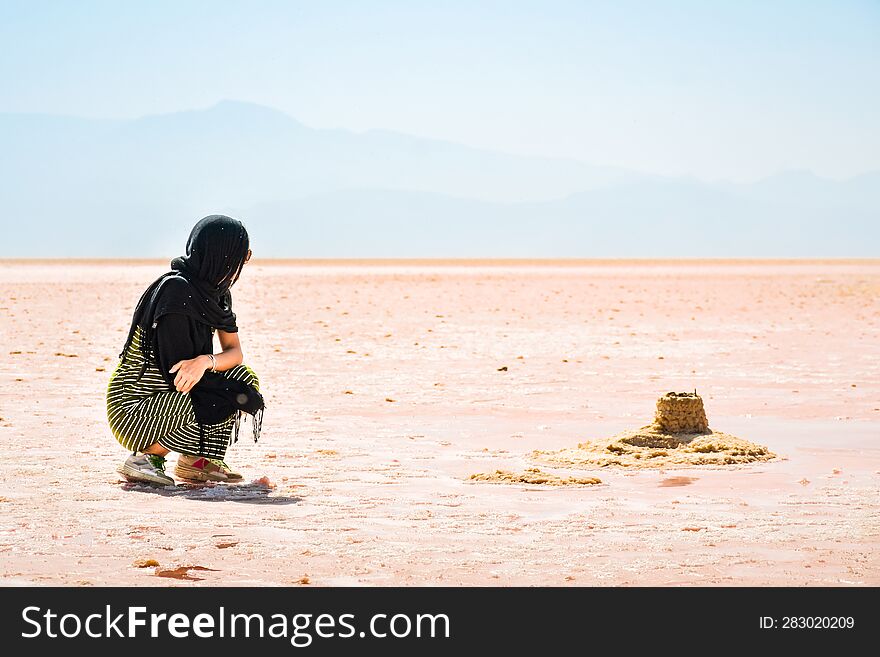 Female traveler tourist sit visiting explore Maharlu pink salt lake shore. Travel destination Iran in Shiraz