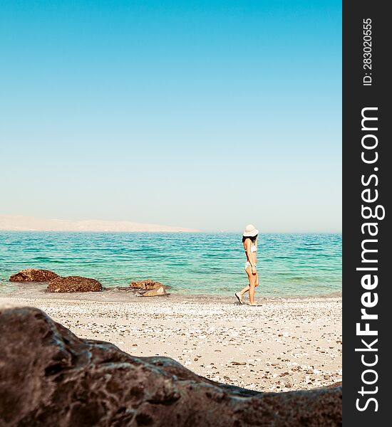 Panorama attractive caucasian tourist woman in white bikini walk on white sand beach alone explore middle east. Persian gulf Mirel