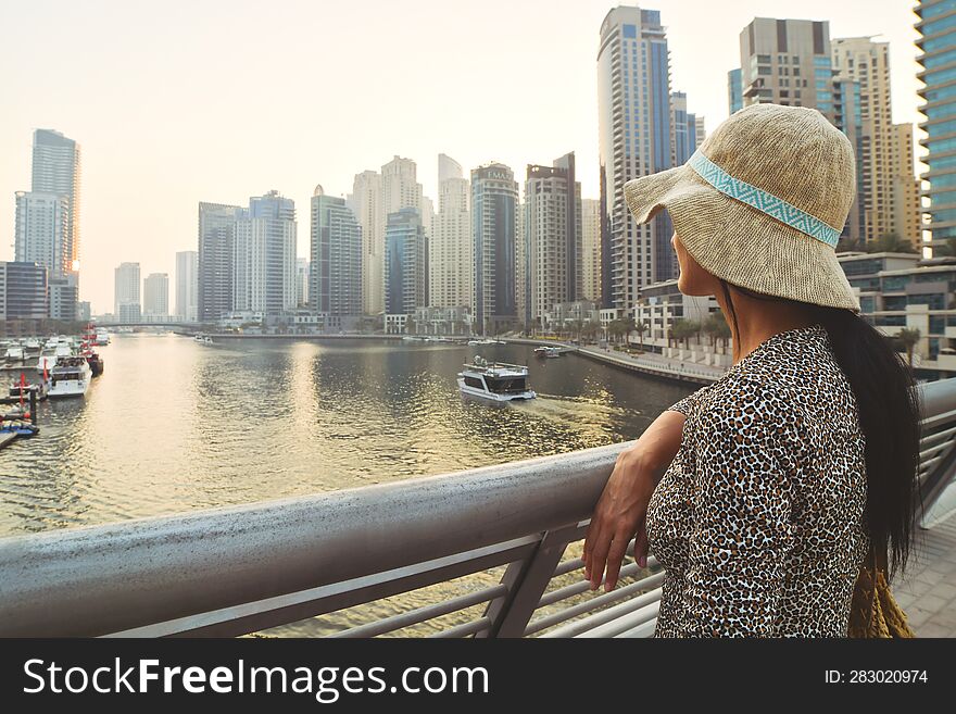 Dubai, UAE - 12th october, 2022: beautiful caucasian tourist woman in fashionable summer dress enjoy Dubai marina in United Arab Emirates. Luxury and comfortable tourism season