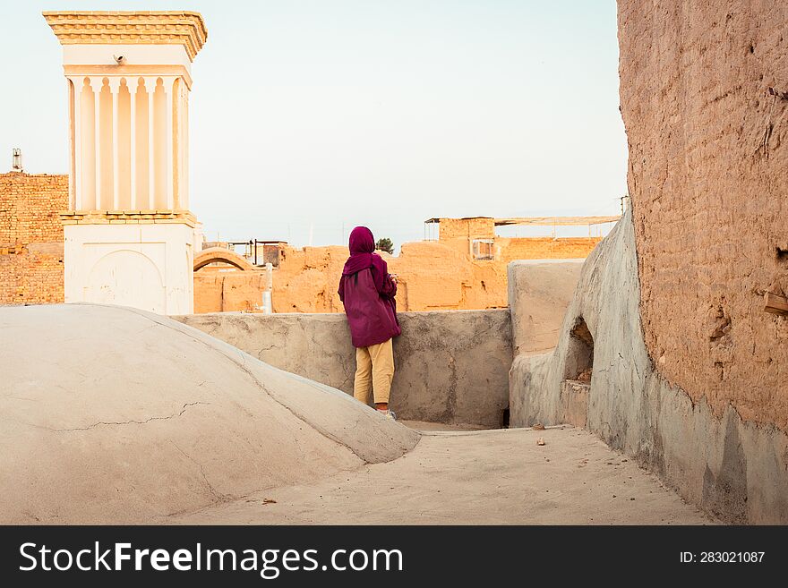 Kashan, Iran - 10th june, 2022: woman visit explore Kashan city neighborhood buildings rooftops background with sunset panorama Explore iran historical heritage concept