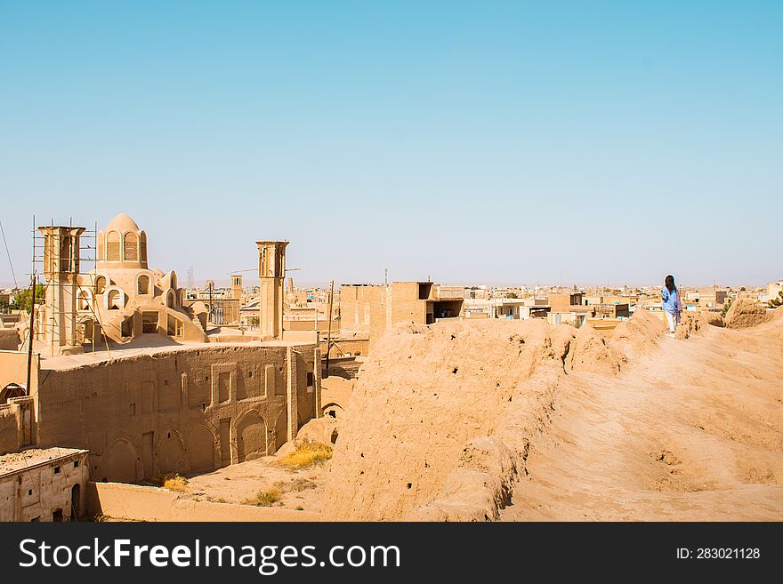 Woman tourist walk on rooftops with panorama from Historic castle in Kashan with city buildings background. Explore iran historical heritage concept