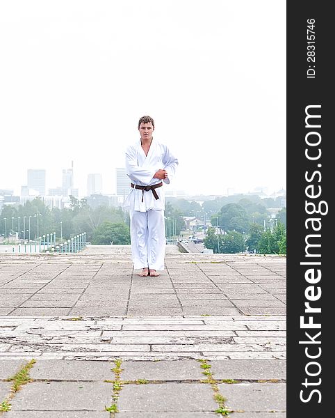 Young karate master doing exercise in the morning on city background