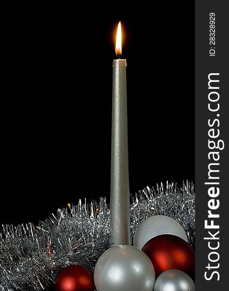 Burning silver candle and christmas balls on a black background. Burning silver candle and christmas balls on a black background