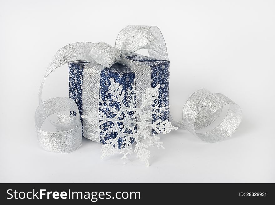 Gift box with silver ribbon and snowflake on a white background. Gift box with silver ribbon and snowflake on a white background