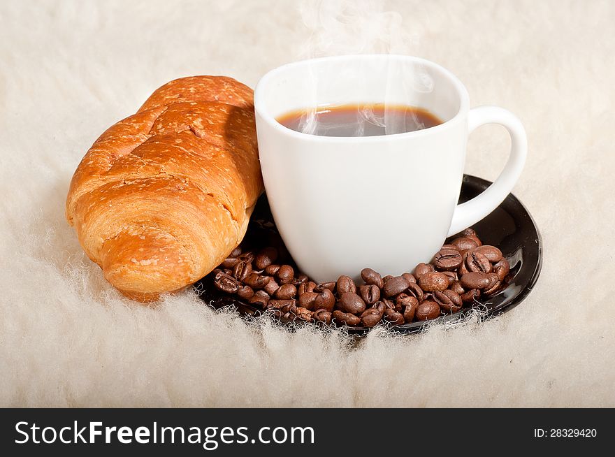 Croissant with coffee and beans on fur background