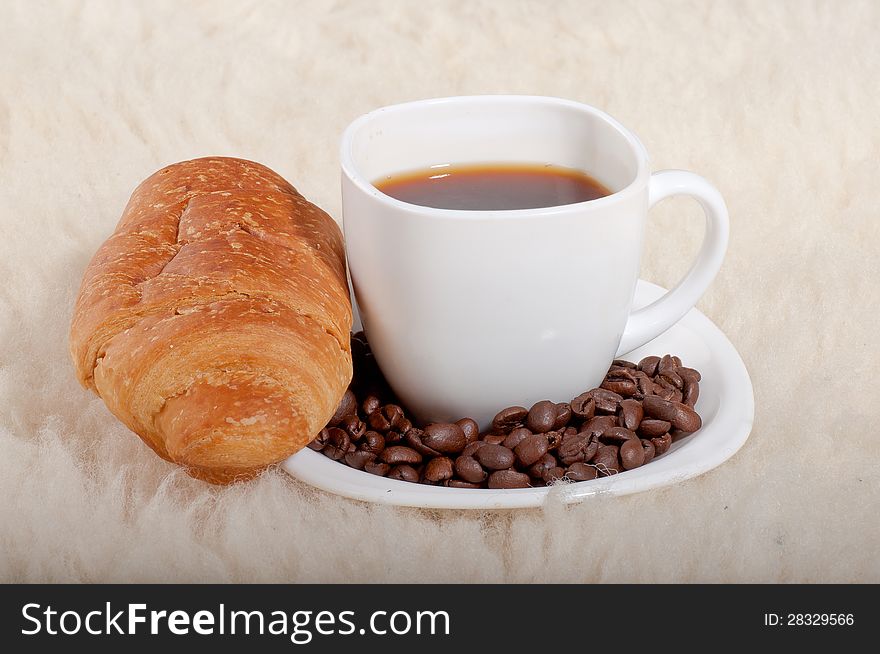 Croissant with coffee and beans on fur background