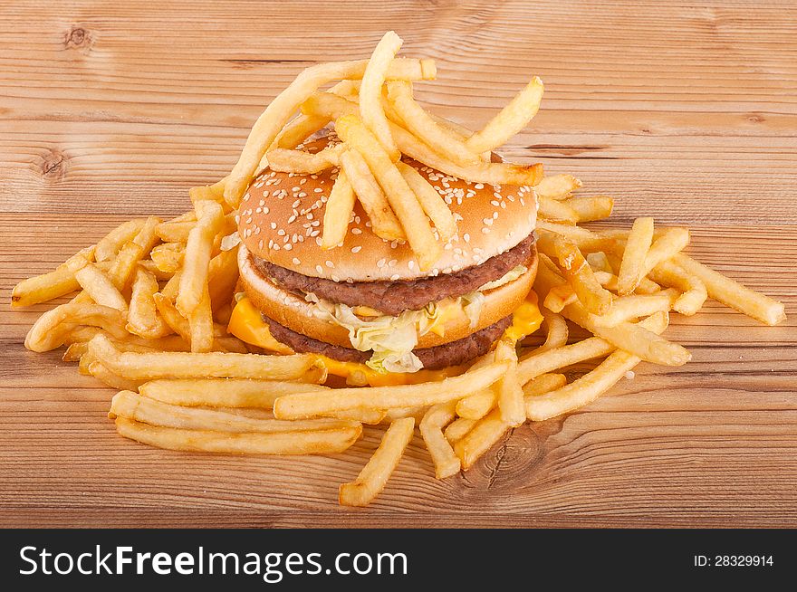 Hamburger and french fries on wooden background.