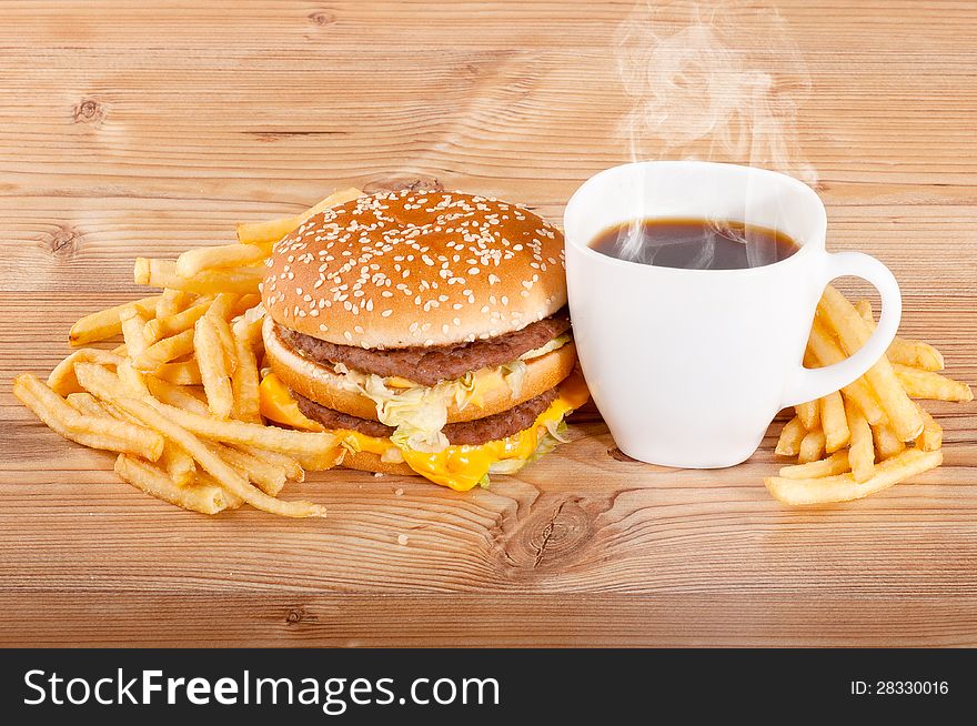 Breakfast set: coffee, hamburger and french fries on wooden background.