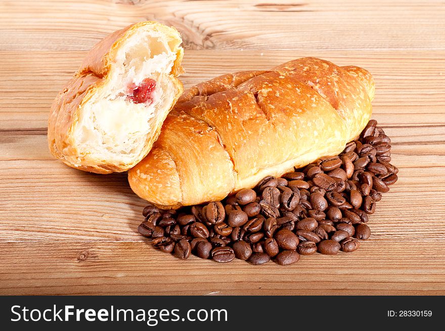 Croissant With Coffee Beans On Wooden Background