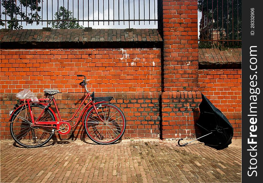 Old bicycle against brick wall with a broken umbrella few minutes after the rain passed