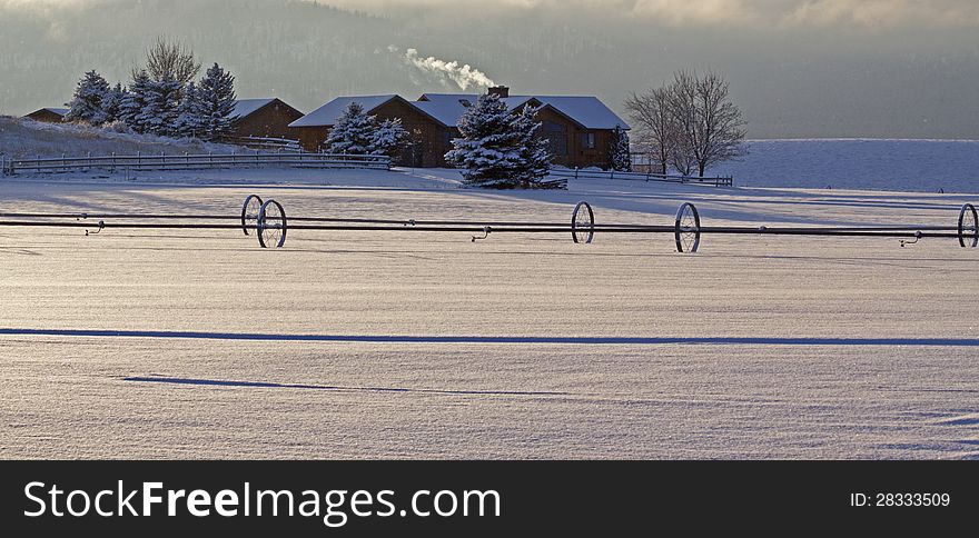 This image of the farm with smoke coming from the chimney, irrigation pipes and shadows in the new fallen snow was taken in NW Montana. This image of the farm with smoke coming from the chimney, irrigation pipes and shadows in the new fallen snow was taken in NW Montana.