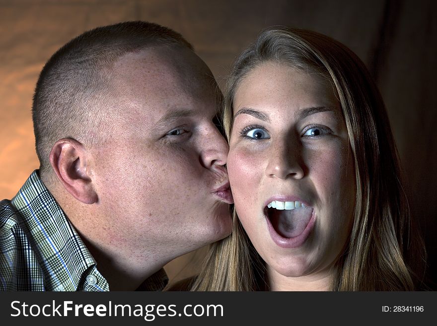 A men kissing a girl on the cheek. Girl has a shocked expression. A men kissing a girl on the cheek. Girl has a shocked expression.