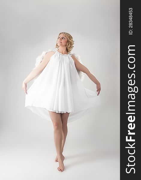 Lovely portrait of young woman wearing angels  wings and smiling over gray background. Lovely portrait of young woman wearing angels  wings and smiling over gray background