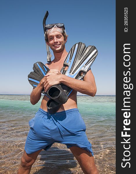 Man on a beach with mask and finns about to swim in ocean. Man on a beach with mask and finns about to swim in ocean