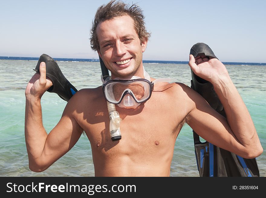 Man on a beach with mask and finns about to swim in ocean. Man on a beach with mask and finns about to swim in ocean