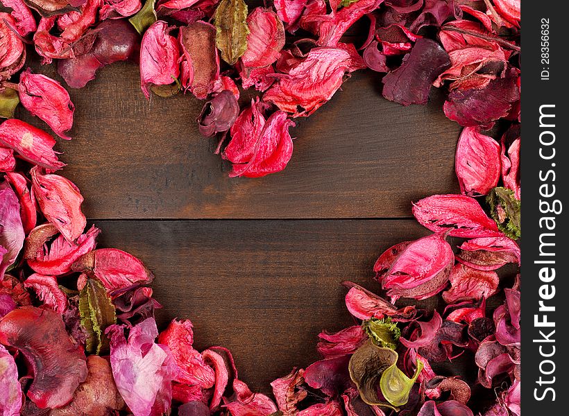 Flower Petals forming a heart shape against wooden background