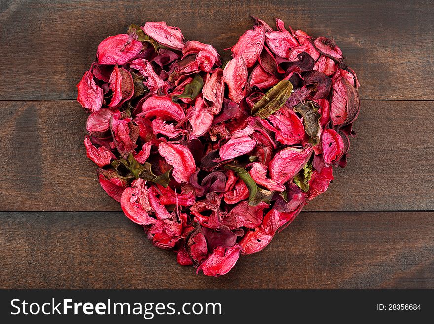 Flower Petals forming a heart shape against wooden background