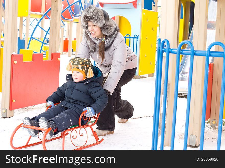 Mother Pushing Her Son On A Winter Sled