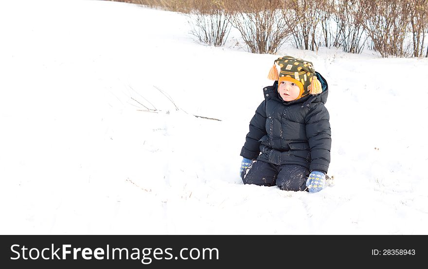 Cute Little Boy Kneeling In Winter Snow