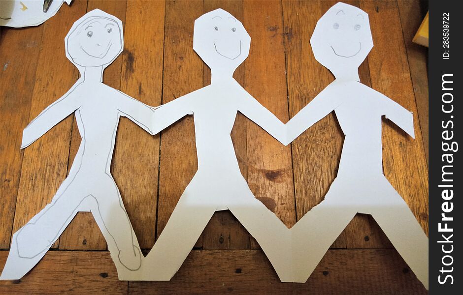 figures cut out of paper are seen holding hands