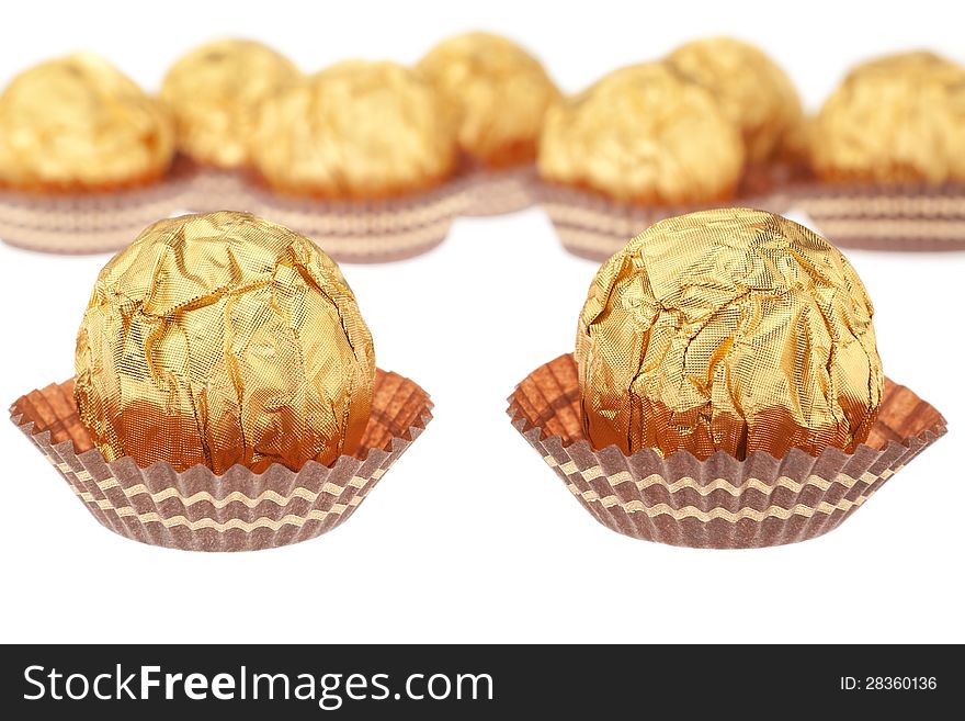 Group chocolate candies wrapped in gold. On a white background.