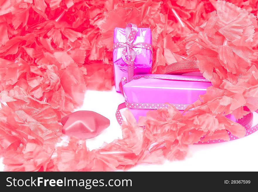 Pair of wrapped gifts on the background of red and pink synthetic petals. Pair of wrapped gifts on the background of red and pink synthetic petals