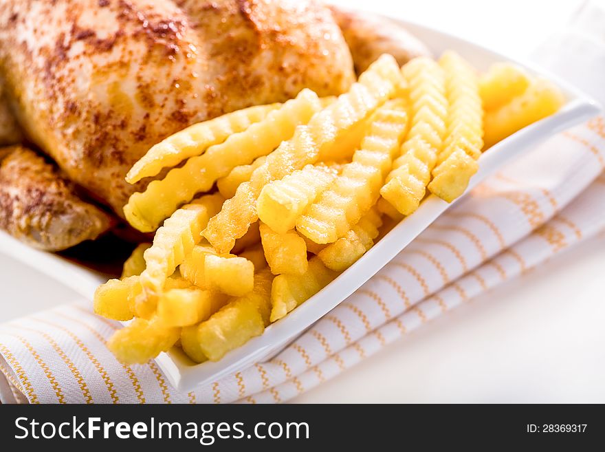 Crisp golden roast chicken served with side dishes of fresh fried crinkly French fries for a delicious meal