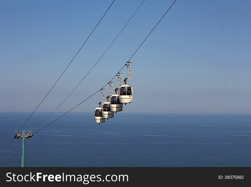 A cablaway with four cable car above the sea and blue sky background. A cablaway with four cable car above the sea and blue sky background