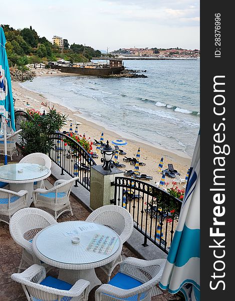 View from a window with small tables and chairs on beach