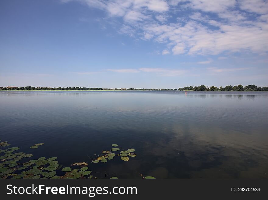 Lake And The Opposite Shore On The Horizon On A Summer Day In The Italian Countryside