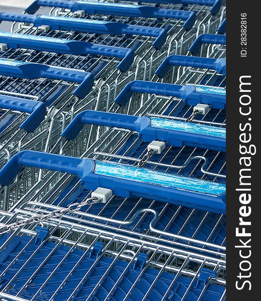 Blue handled steel supermarket carts stacked together. Blue handled steel supermarket carts stacked together