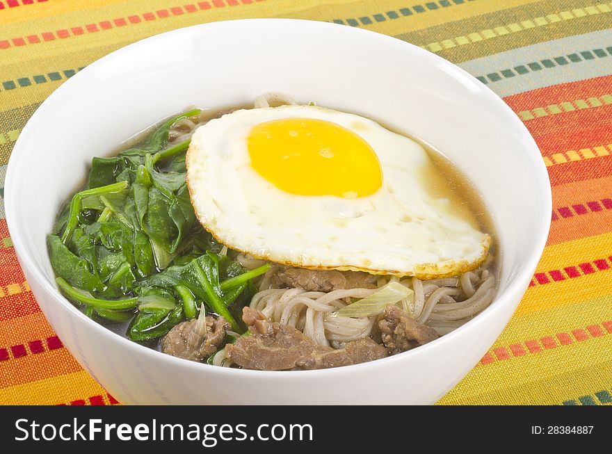 Bowl of buckwheat noodle soup with spinach, beef and fried egg. Bowl of buckwheat noodle soup with spinach, beef and fried egg.