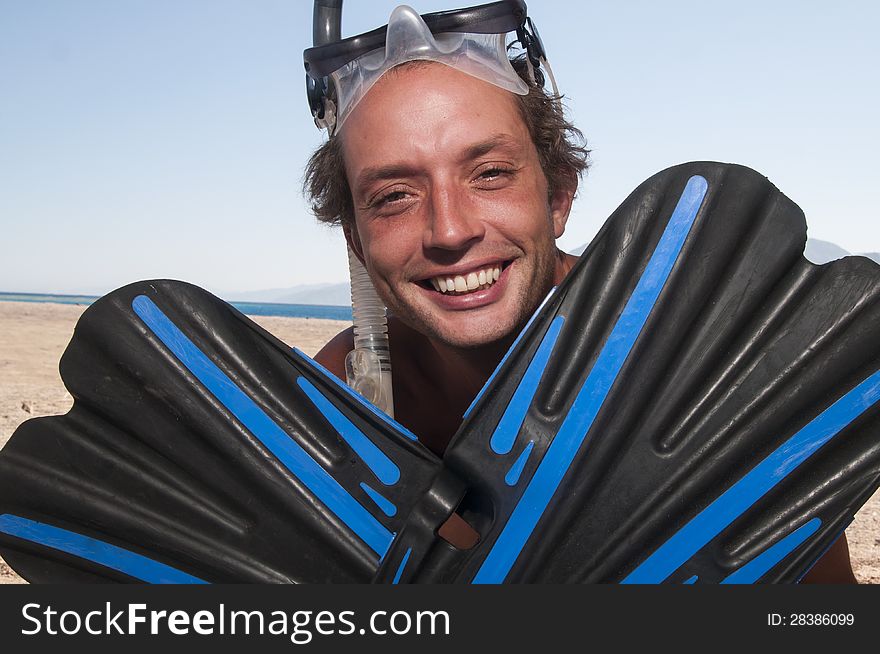 Man on a beach with mask and finns about to go swimming and snorkeling. Man on a beach with mask and finns about to go swimming and snorkeling