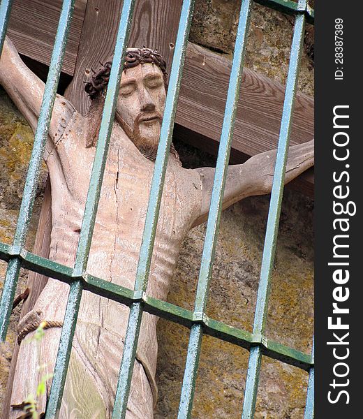 Statue of jesus christ on the cross behind bars