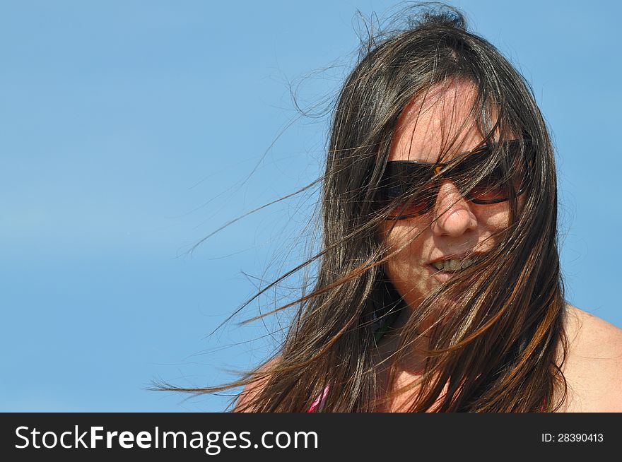 A woman with sunglasses is looking the camera during a summer day. A woman with sunglasses is looking the camera during a summer day