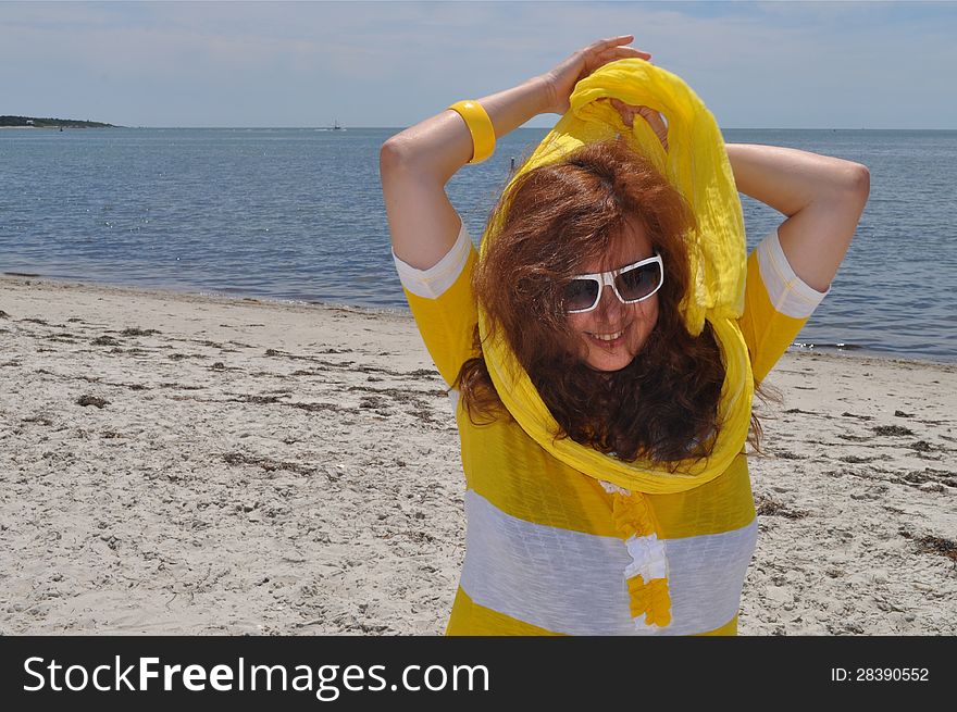 A woman is placing her yellow scarf at a Cape Cod beach. A woman is placing her yellow scarf at a Cape Cod beach.