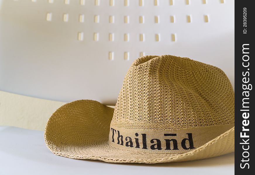 A hat with Thailand word is on a white chair. A hat with Thailand word is on a white chair