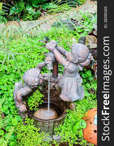 Boy and girl with well sculpture in botanic garden, Thailand