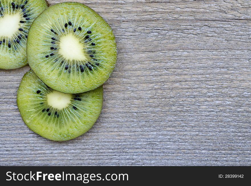 Fresh kiwi slices on wood texture .