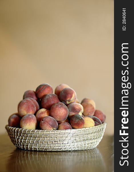 A basket overflowing with peaches, sitting on a wooden table in a rustic kitchen. A basket overflowing with peaches, sitting on a wooden table in a rustic kitchen