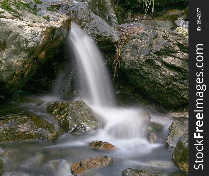 A long exposure of a small waterfall with misty water flow effect. A long exposure of a small waterfall with misty water flow effect